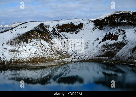 Neve ed escursionisti sul cratere di esplosione vulcanica Viti Krafla e sul lago Aqua Blue presso l'area geotermica di Myvatnseldar, Islanda del Nord Foto Stock