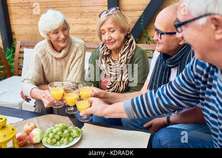 Gruppo di amici in pensione la tostatura a pranzo Foto Stock