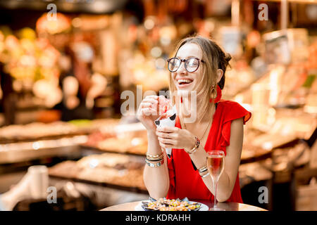 Donna spagnola a mangiare jamon al mercato Foto Stock
