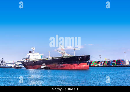 Una petroliera vuota viene navigata fuori dal porto di Long Beach da due potenti rimorchiatori durante una giornata di sole Foto Stock