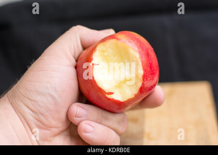 Apple essendo tenuto in una mano di sesso maschile con il morso preso fuori di esso. Foto Stock