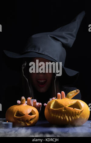 Halloween strega con una magica zucca. bella giovane donna in streghe hat e costume holding scolpito. zucca Halloween art design. Foto Stock