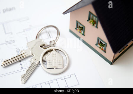 Chiave di casa su una casa pendente a forma. agente immobiliare concetto su sfondo bianco Foto Stock