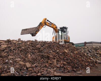 Un escavatore jcb sulla sommità di una pila di macerie Foto Stock
