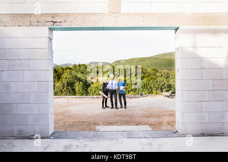 Architetto, ingegnere civile e lavoratore guardando i piani e progetti, in cui si discuterà di problemi sul sito di costruzione. Foto Stock