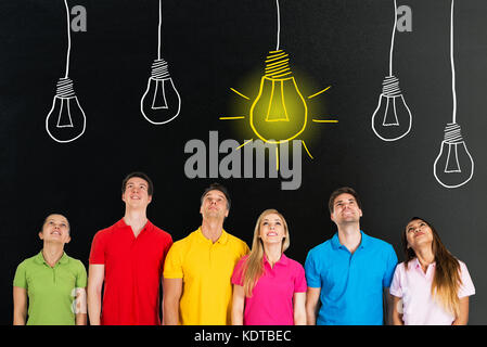 Un gruppo di persone in piedi in fila che guarda l'idea brillante concetto sulla lavagna Foto Stock