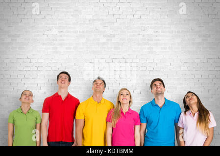 Gruppo di diverse persone felici in piedi contro Un muro di guardare in alto Foto Stock