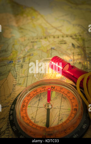 Bussola mostra la direzione sulla mappa topografica con fischietto di soccorso, la navigazione di notte, la luce del flash illuminato, profondità di campo, focus sul nord Foto Stock