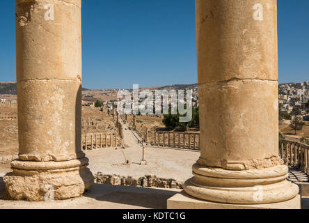 Cerca tra le colonne a ovale Plaza e il Cardo, città romana di Jerash, antica Gerasa, sito archeologico in Giordania, Medio Oriente Foto Stock