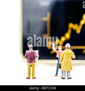 Il concetto di business, primo piano delle figurine in miniatura di uomini di affari in piedi di fronte a grande schermo sfocati con prezzo di stock market grafico con indicatore Foto Stock