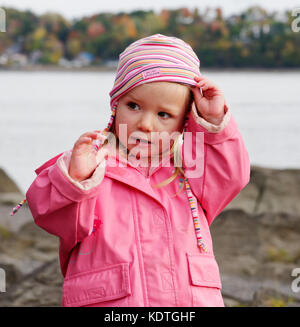 Una bambina di 3 anni che indossa una giacca impermeabile rosa e hat Foto Stock