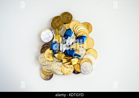 Pila di colorati e dreidels hanukkah monete isolato su bianco Foto Stock