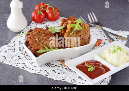 Uova fritte frittelle di vegetali con pomodoro e salsa di yogurt in una ciotola bianco su un grigio Sfondo astratto. cibo sano. una sana prima colazione. Foto Stock