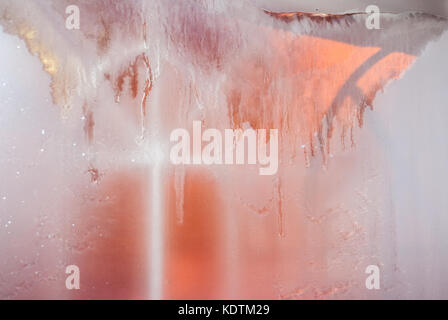 Inverno sfondo sfocato. congelati finestra con lo scongelamento di macchie che scorrono giù . shot dall'interno. finestra è illuminato dall'esterno. Foto Stock