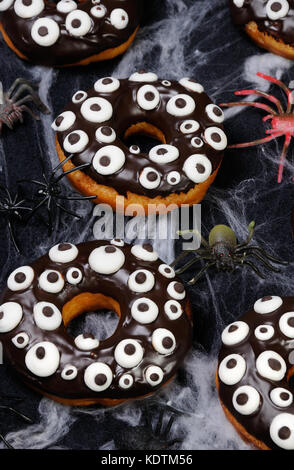 Donuts con glassa di cioccolato decorate googly occhi su halloween Foto Stock
