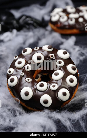 Donuts con glassa di cioccolato decorate googly occhi su halloween Foto Stock