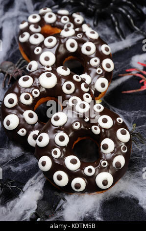Donuts con glassa di cioccolato decorate googly occhi su halloween Foto Stock