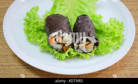 La cucina giapponese, vagetarian tradizionale di riso giapponese maki sushi roll roba con tofu e carote avvolte in nori alghe servita sulla quercia verde. Foto Stock