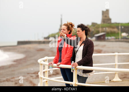 Aberystwyth, ceredigion, Wales, Regno Unito. Xvi oct, 2017. uk meteo. forti venti di prelevare sul West Wales coast a aberystwyth come tempesta ofelia approcci - i residenti locali louise e brogan guarda come la tempesta viene in off sul mare irlandese. Credito: Steven maggio/alamy live news Foto Stock