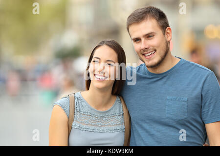 Vista frontale di una coppia felice di camminare sulla strada e guardando lontano Foto Stock