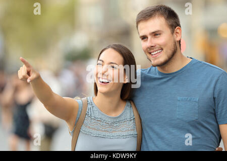 Coppia felice di trovare la posizione e puntando al lato di camminare sulla strada Foto Stock