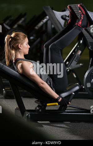 Donna sportive utilizzando pesi pressa per gambe. palestra. Foto Stock