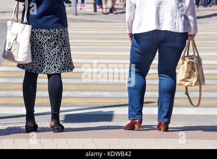 La donna è in attesa di attraversare la strada sulla soleggiata giornata estiva Foto Stock