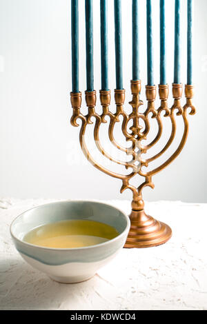 Il Menorah Hanukkah in ottone con candele di blu e il burro in una terrina vista laterale verticale Foto Stock