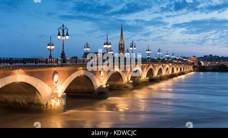 Pont de Pierre che attraversano il fiume Garonne al crepuscolo con Basilique Saint-Michel oltre, Bordeaux Aquitania, Francia Foto Stock