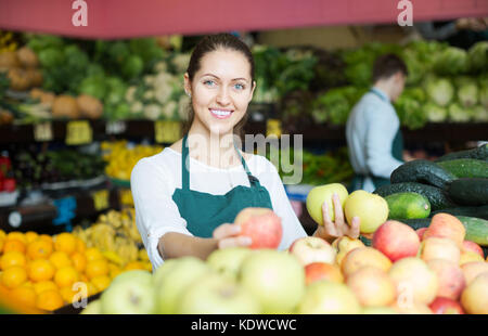 Donna sorridente roba in vendita della catenaria dolce di mele stagionale al marketplace Foto Stock