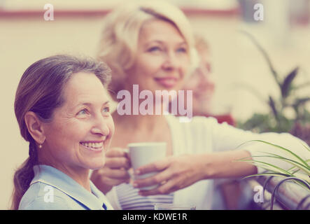 Felice anziani colleghi femmina avente la pausa pranzo al patio e bere il tè Foto Stock