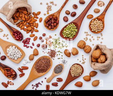 Vari tipi di legumi e nutshells in cucchiai e la canapa sacco sacchi. i kernel di noci, nocciole, mandorle ,brown pinto ,i fagioli di soia ,semi di lino ,chia ,capretto rosso Foto Stock
