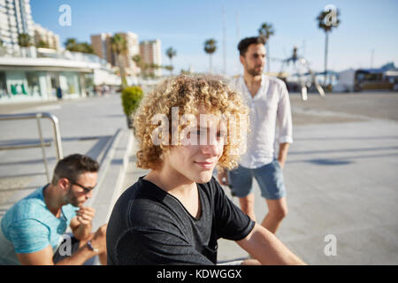 Ritratto di giovane uomo con gli amici in attesa fuori smirking Foto Stock