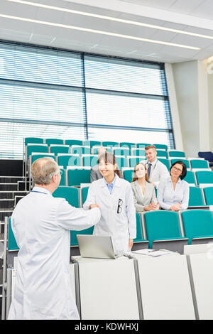 Il professor congratularmi con lo studente per il successo della scuola medica exam Foto Stock