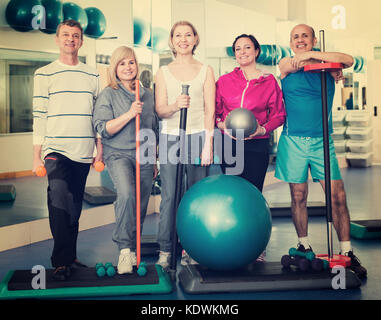 Gruppo di gioiosa maturo uomini e donne dopo esercizio in palestra con attrezzature sportive Foto Stock