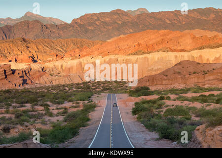 Un solitario auto sulla strada verso il basso la quebrada de la conches, Valles Calchaquies, provincia di Salta, Argentina Foto Stock