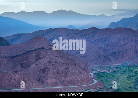 La lunga strada tortuosa verso il basso la Quebrada de la Conches dal Mirador Tres Cruces in Valles Calchaquies, Provincia di Salta, Argentina Foto Stock