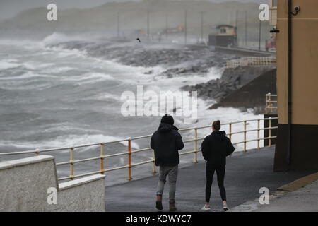 La gente guarda le onde e gli spruzzi di mare a Lahinch nella contea di Clare sulla costa occidentale dell'Irlanda mentre l'uragano Ophelia colpisce il Regno Unito e l'Irlanda con raffiche fino a 80 mph. Foto Stock