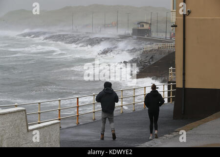 La gente guarda le onde e sea spray a lahinch nella contea di Clare sulla costa occidentale dell'Irlanda come uragano ofelia colpisce il Regno Unito e l'Irlanda con raffiche fino a 80km/h. Foto Stock