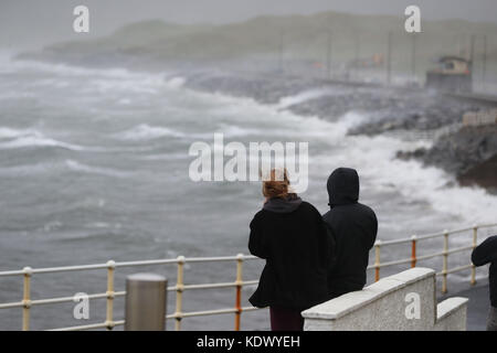 La gente guarda le onde e gli spruzzi di mare a Lahinch nella contea di Clare sulla costa occidentale dell'Irlanda mentre l'uragano Ophelia colpisce il Regno Unito e l'Irlanda con raffiche fino a 80 mph. Foto Stock