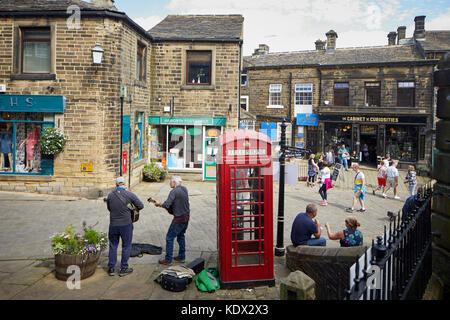 Pennines village, Haworth nel West Yorkshire, Inghilterra. case a schiera e le aziende per la ripida strada principale Foto Stock