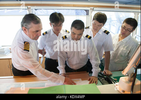 Il capitano e gli ufficiali di discutere i piani di navigazione a bordo di una nave mercantile Foto Stock