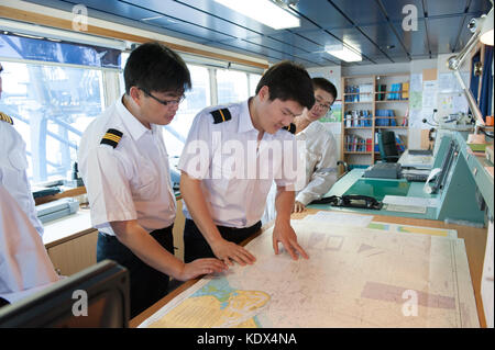 Il capitano e gli ufficiali di discutere i piani di navigazione a bordo di una nave mercantile Foto Stock