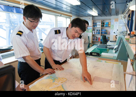 Il capitano e gli ufficiali di discutere i piani di navigazione a bordo di una nave mercantile Foto Stock