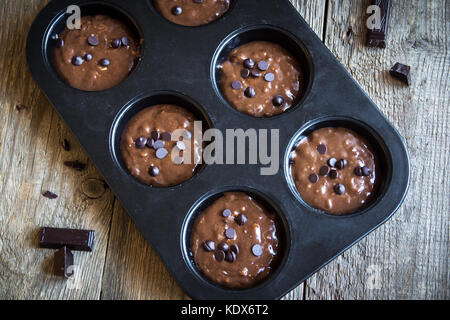 In casa di base brownie o muffin al cioccolato impasto crudo nella teglia di cottura. (cottura) cioccolato artigianale muffin, tortine o brownies. Foto Stock