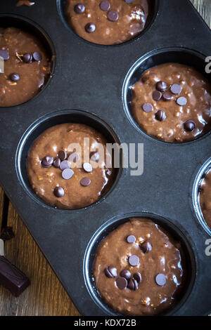 In casa di base brownie o muffin al cioccolato impasto crudo nella teglia di cottura. (cottura) cioccolato artigianale muffin, tortine o brownies. Foto Stock