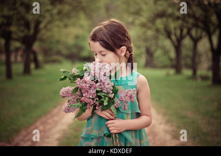 Bella ragazza che tiene un bouquet di fiori e puzza. Occhi chiusi, immagine romantica. Foto Stock