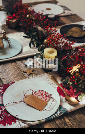 Tavola rustica di Natale con stoviglie vuote artigianali in ceramica, piatti  e ciotole, decorazioni d'angelo di Natale, bicchieri di succo rosso, rami  verdi e Foto stock - Alamy