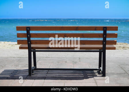 Svuotare il resto in legno banco a riva del mare dalla soleggiata giornata estiva Foto Stock