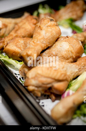 Chiusura del pollo arrosto con bastoncini di tamburo in corrispondenza di un buffet su un vassoio nero con lattuga come una decorazione Foto Stock